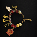 Pat Goffe Collections gold-tone charm bracelet featuring red beads, Greek letters, and a detailed crest charm.