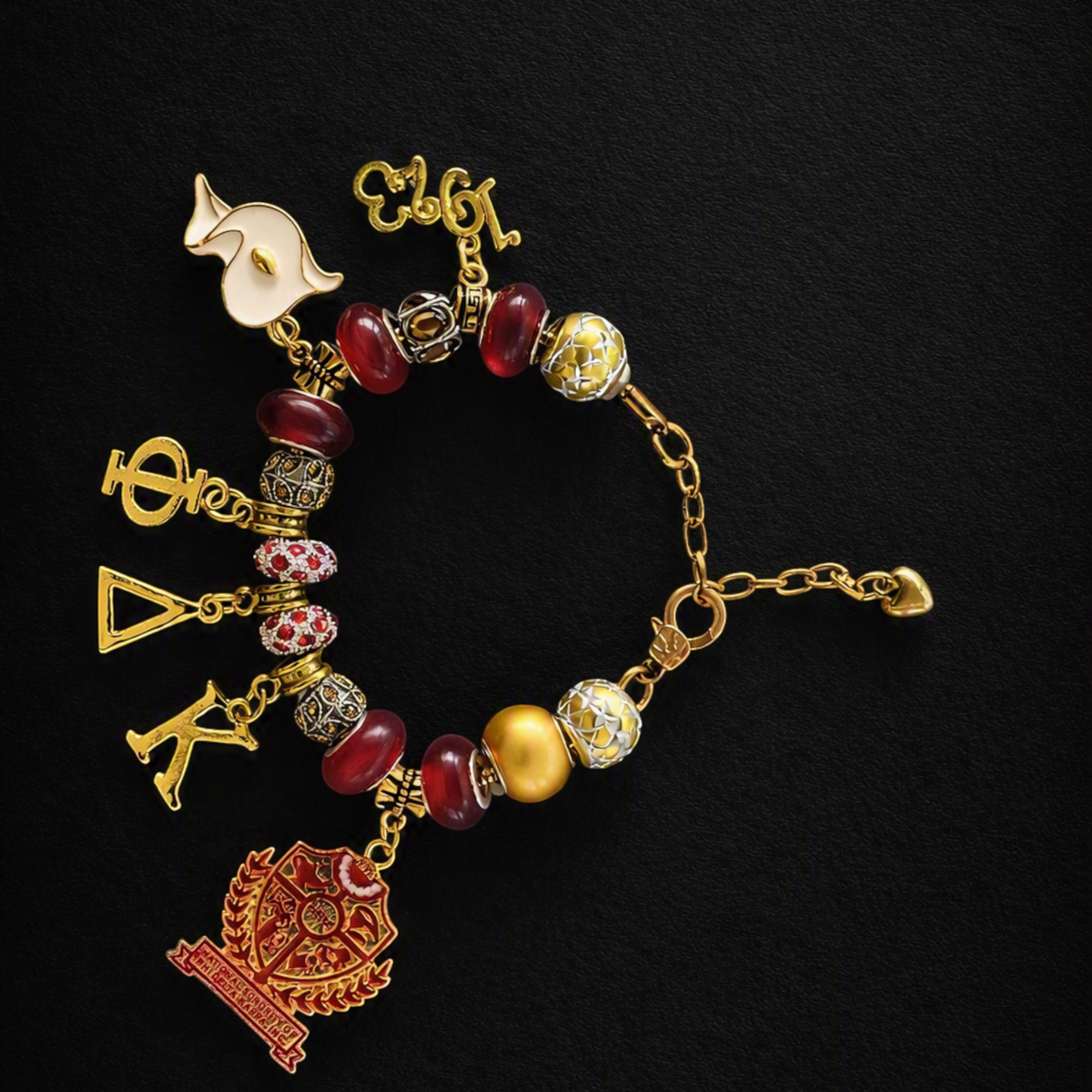 Pat Goffe Collections gold-tone charm bracelet featuring red beads, Greek letters, and a detailed crest charm.