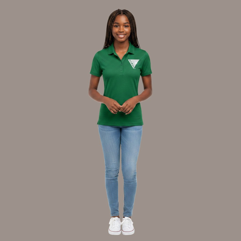 A woman wearing a Pat Goffe Collections green short sleeve performance polo shirt with light blue jeans and sneakers.