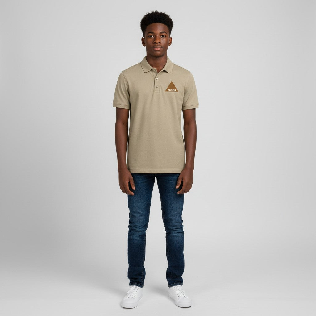 A man wearing a Pat Goffe Collections khaki short sleeve polo shirt with a triangle logo, paired with blue jeans.