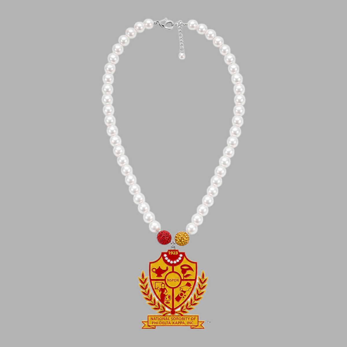 Pat Goffe Collections pearl necklace featuring a red and gold NSPDK shield pendant with crystal accents